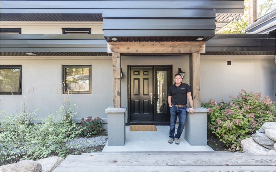 Licensed contractor John DeCarli standing against pillar outside front porch of a new house